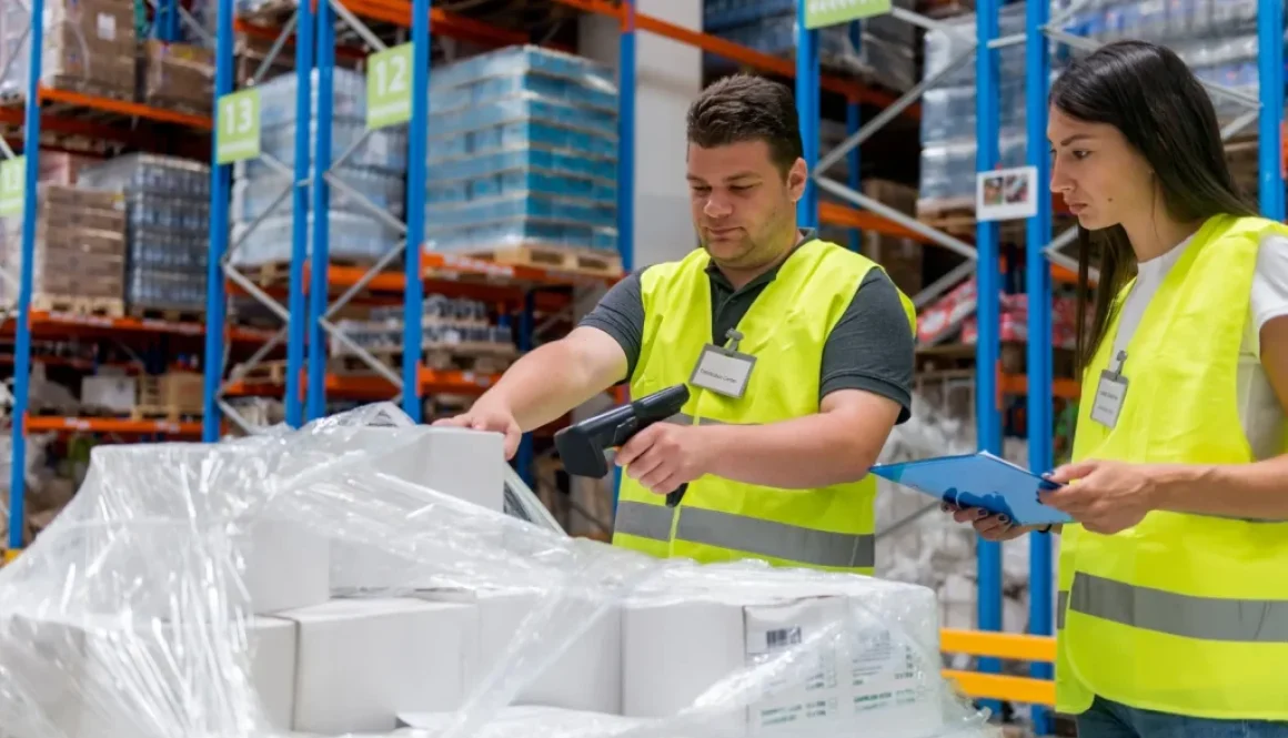 Warehouse worker using UHF RFID reader to scan tagged pallets and equipment