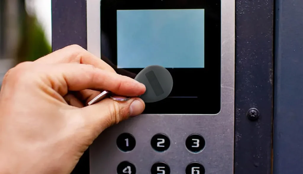 Mano aproximando un llavero RFID a un lector con teclado integrado, guiando a través de los pasos de funcionamiento del dispositivo.