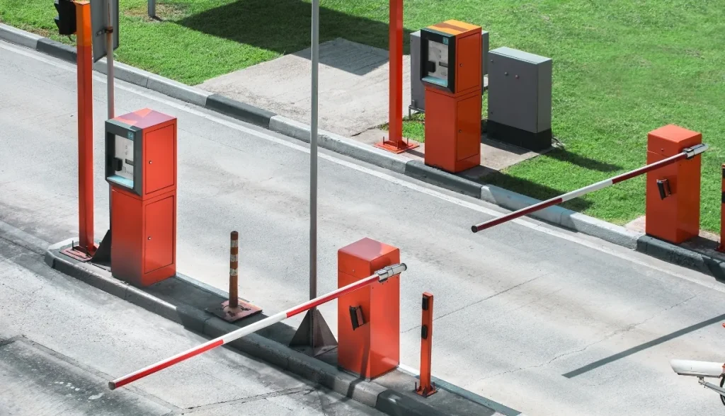 Overhead view of parking lot access control barriers with orange readers, representing real-world RFID vehicle access systems.