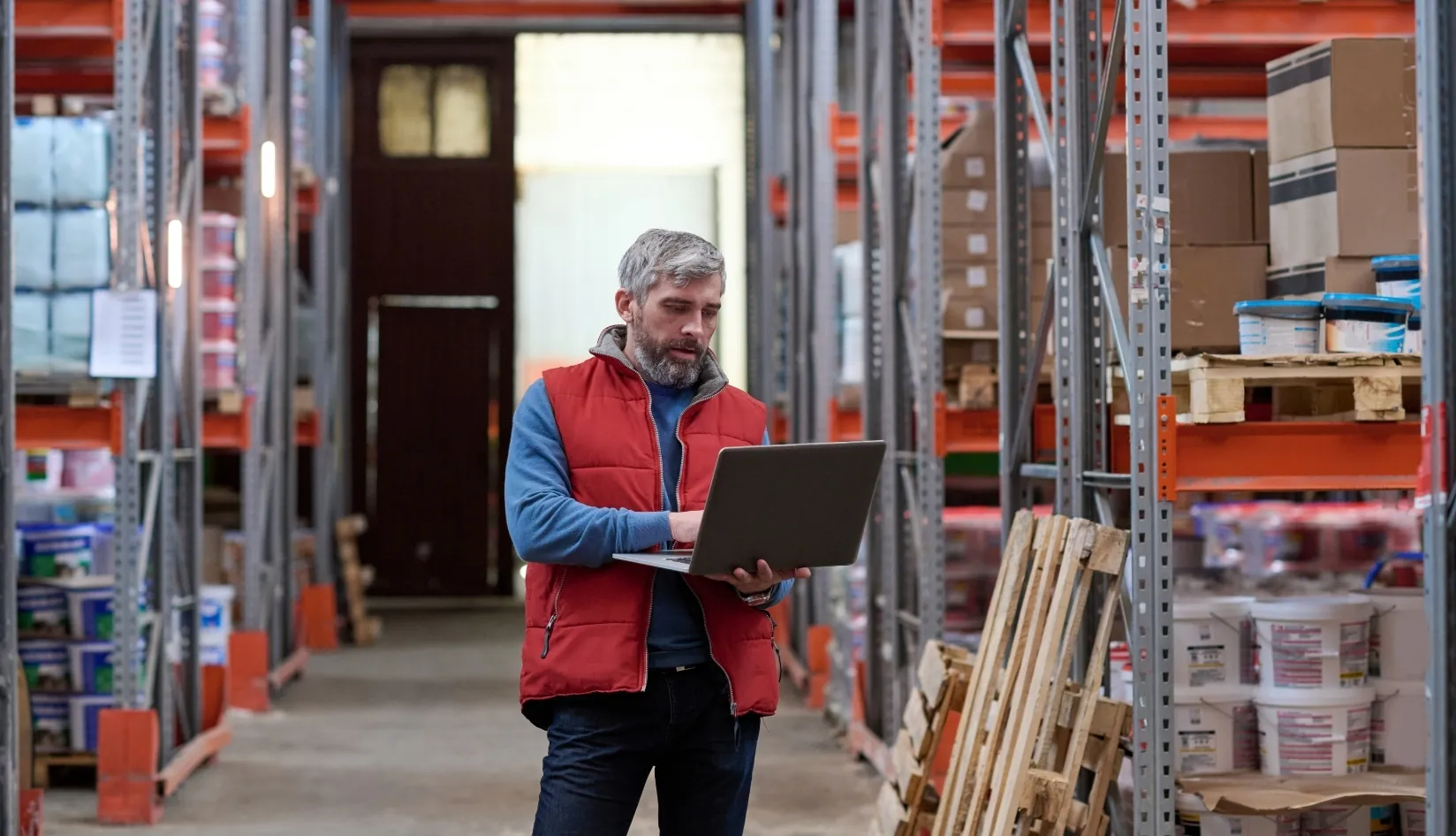 How to Choose the Right UHF RFID Chip for Your RFID Tags A warehouse manager using a laptop to review inventory, representing the practical application of choosing the right UHF RFID chip for logistics and warehousing use cases.