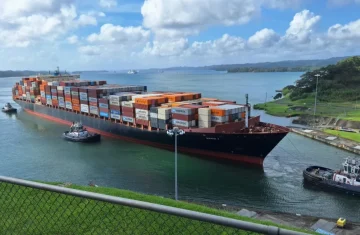 What Are RFID Security Tags Key Features You Should Look For Large container ship loaded with colorful shipping containers transiting a canal, guided by tugboats, representing logistics and supply chain industries.