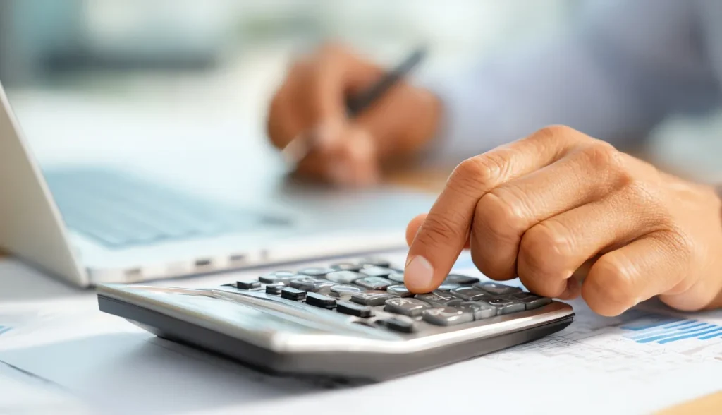 Person pressing calculator keys with financial documents on a desk.
