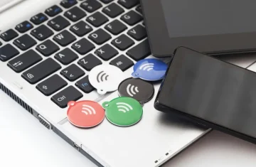 NFC Tag Dimensions vs Read Range What’s the Relationship NFC tag dimensions comparison with colorful NFC tags on a laptop next to smartphone and tablet, illustrating common NFC tag form factors.
