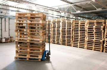 RFID Pallet Tracking How It Works, Benefits, Challenges, and Best Practices Stacks of wooden pallets in a warehouse, representing RFID pallet tracking for inventory and asset management.