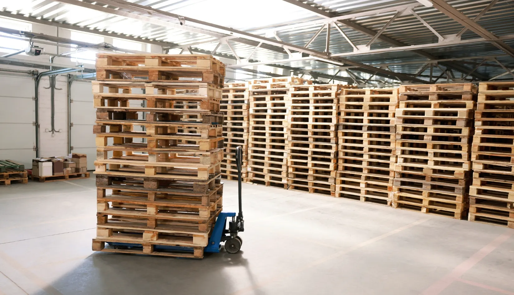 RFID Pallet Tracking How It Works, Benefits, Challenges, and Best Practices Stacks of wooden pallets in a warehouse, representing RFID pallet tracking for inventory and asset management.