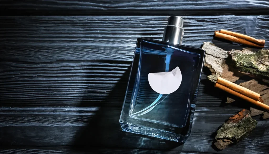 Square transparent perfume bottle with brand sticker on dark wooden surface, luxury consumer goods secured with tamper proof RFID tags.