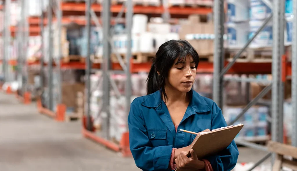 Warehouse staff holding clipboard conducting inventory check in industrial storage warehouse, asset tracking with tamper proof RFID tags.