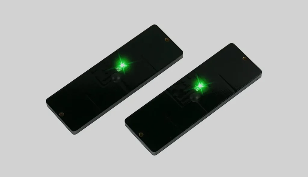 Two black rectangular hard‑case RFID LED tags with glowing green indicator lights for asset tracking.